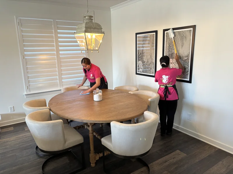 Two Hola Maids team members cleaning a dining table and nearby surfaces